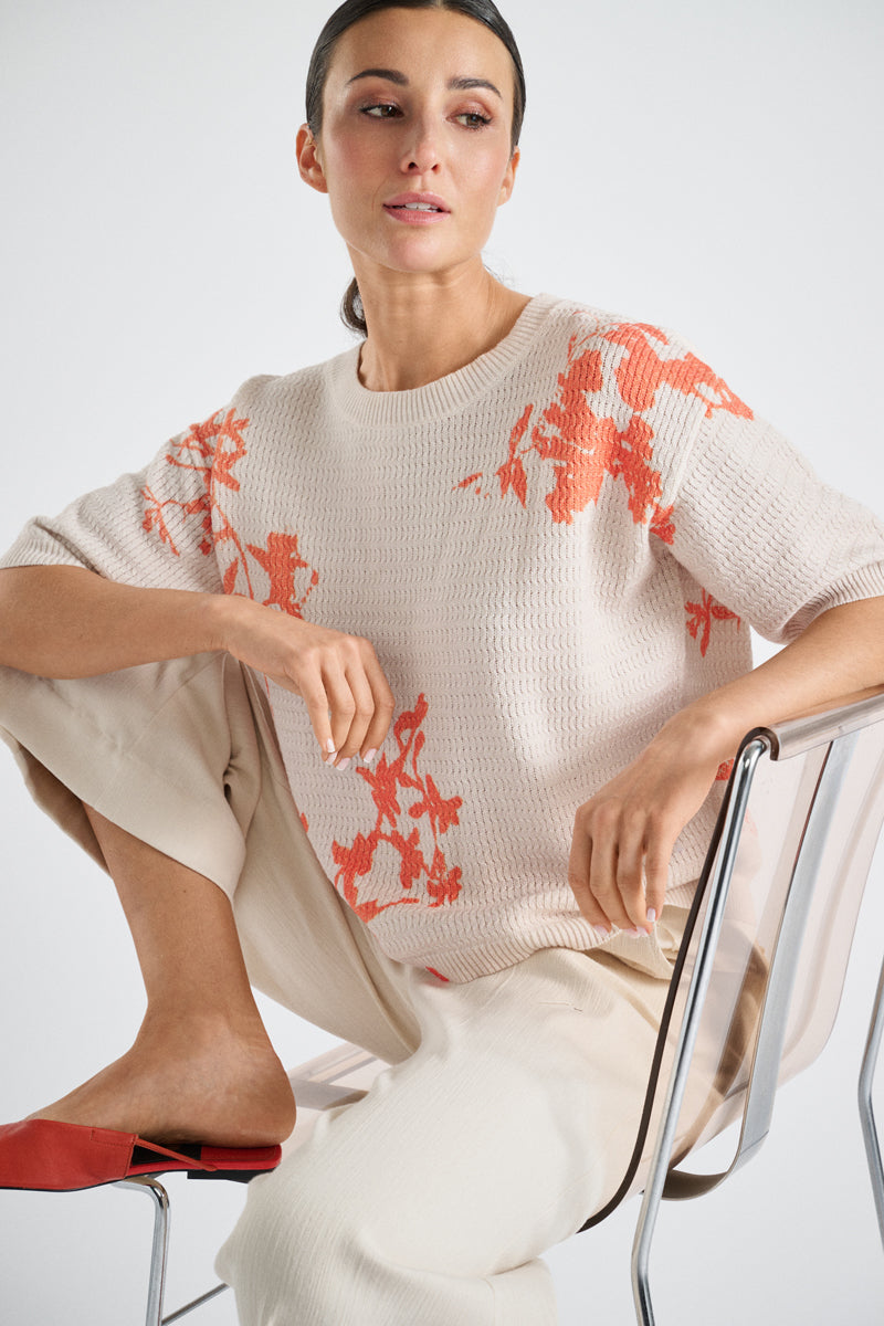 Crèmekleurige trui met oranje bloem