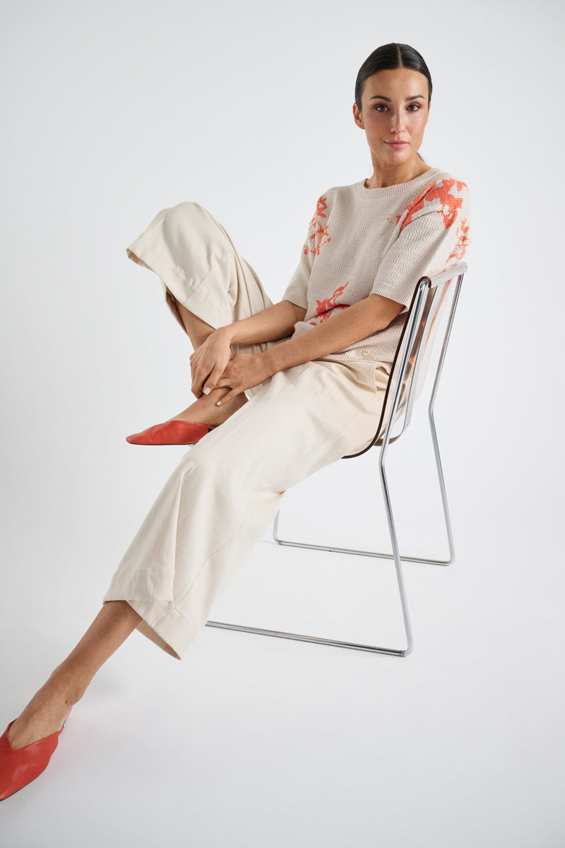 Crèmekleurige trui met oranje bloem